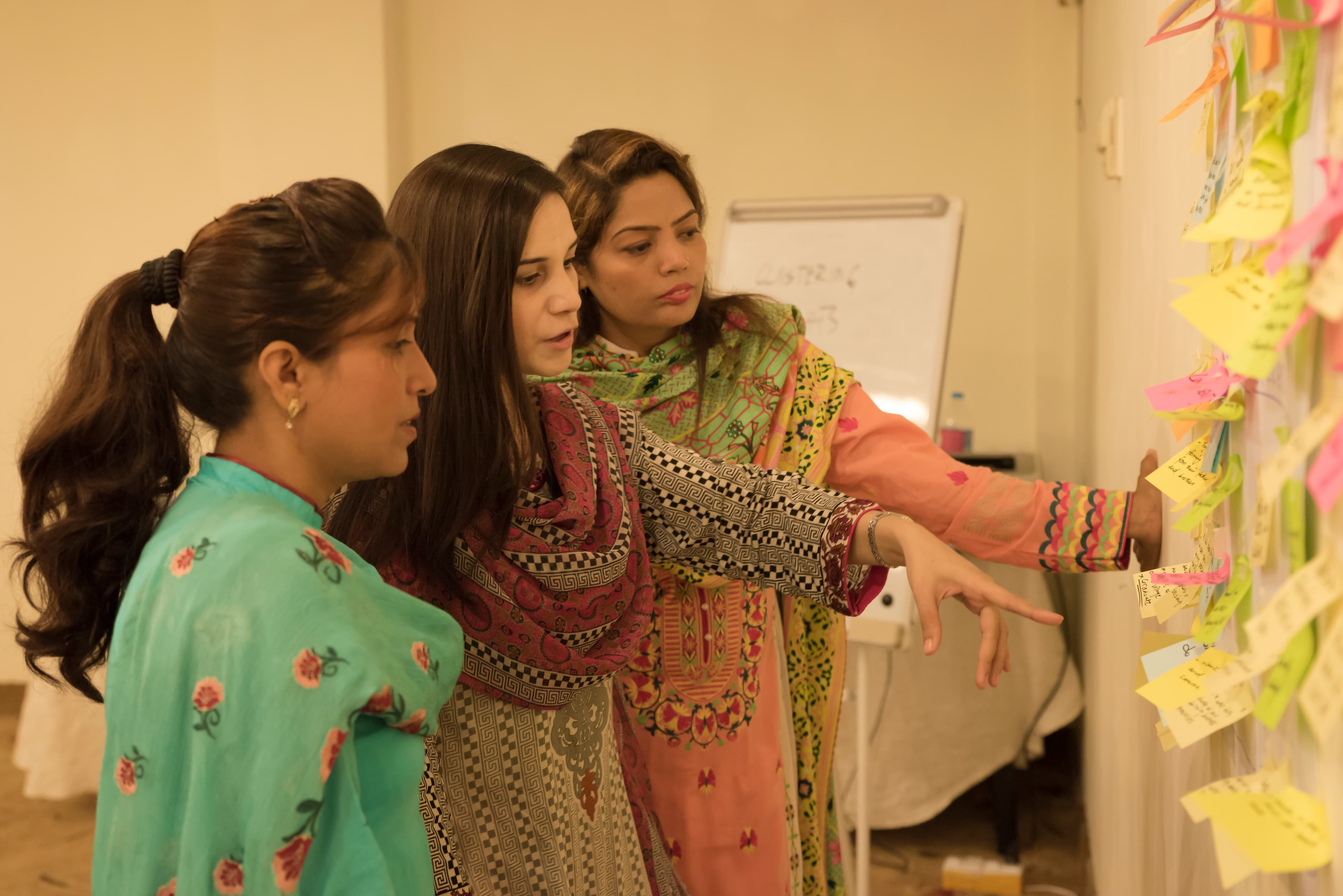 Women participants writing challenge statements during an ideation session