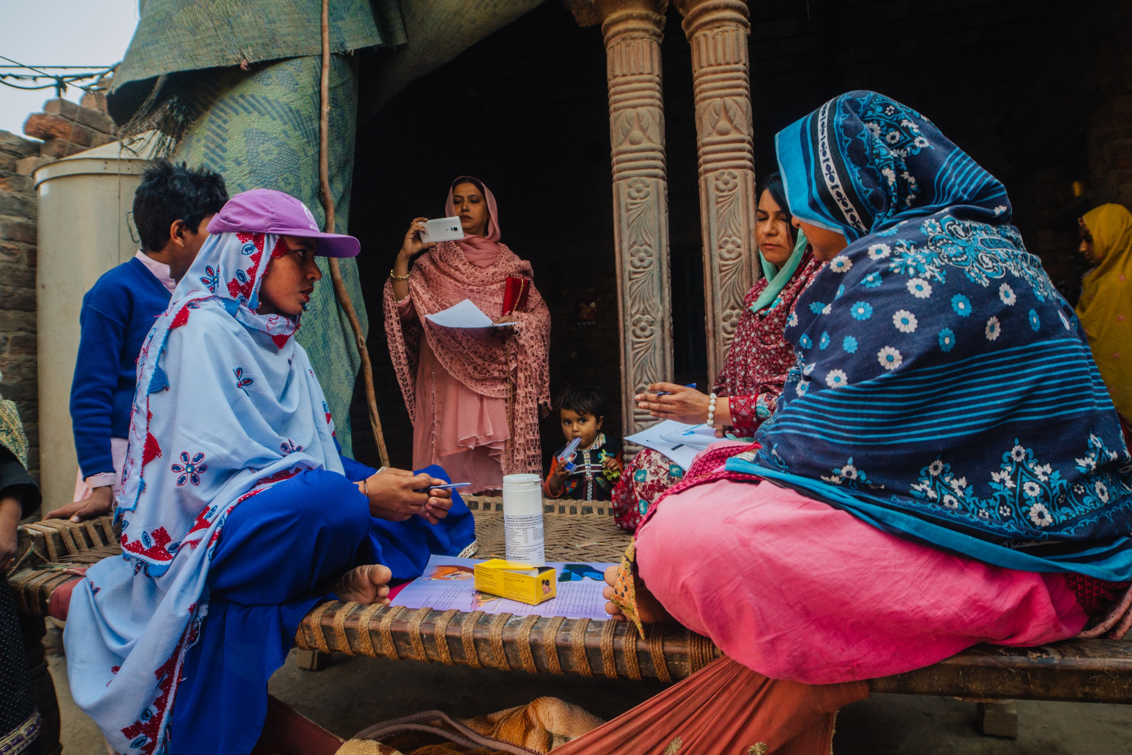 Frontline worker demonstrating nutrition practices to mothers in a village courtyard
